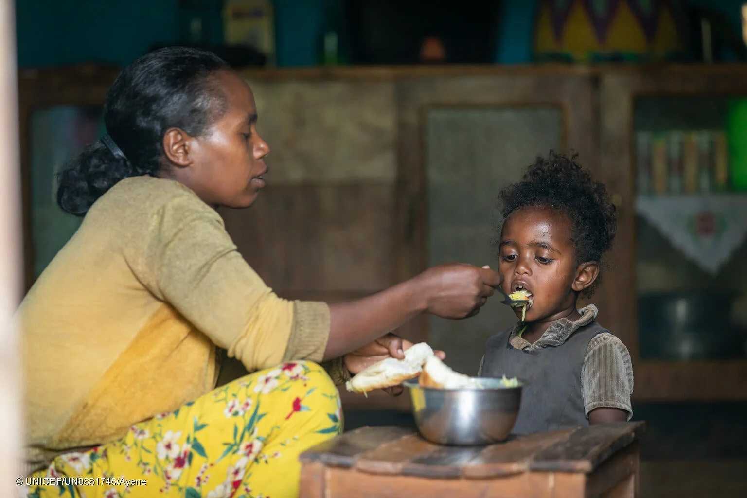 母親が幼い子どもにスプーンで食事を与えている様子